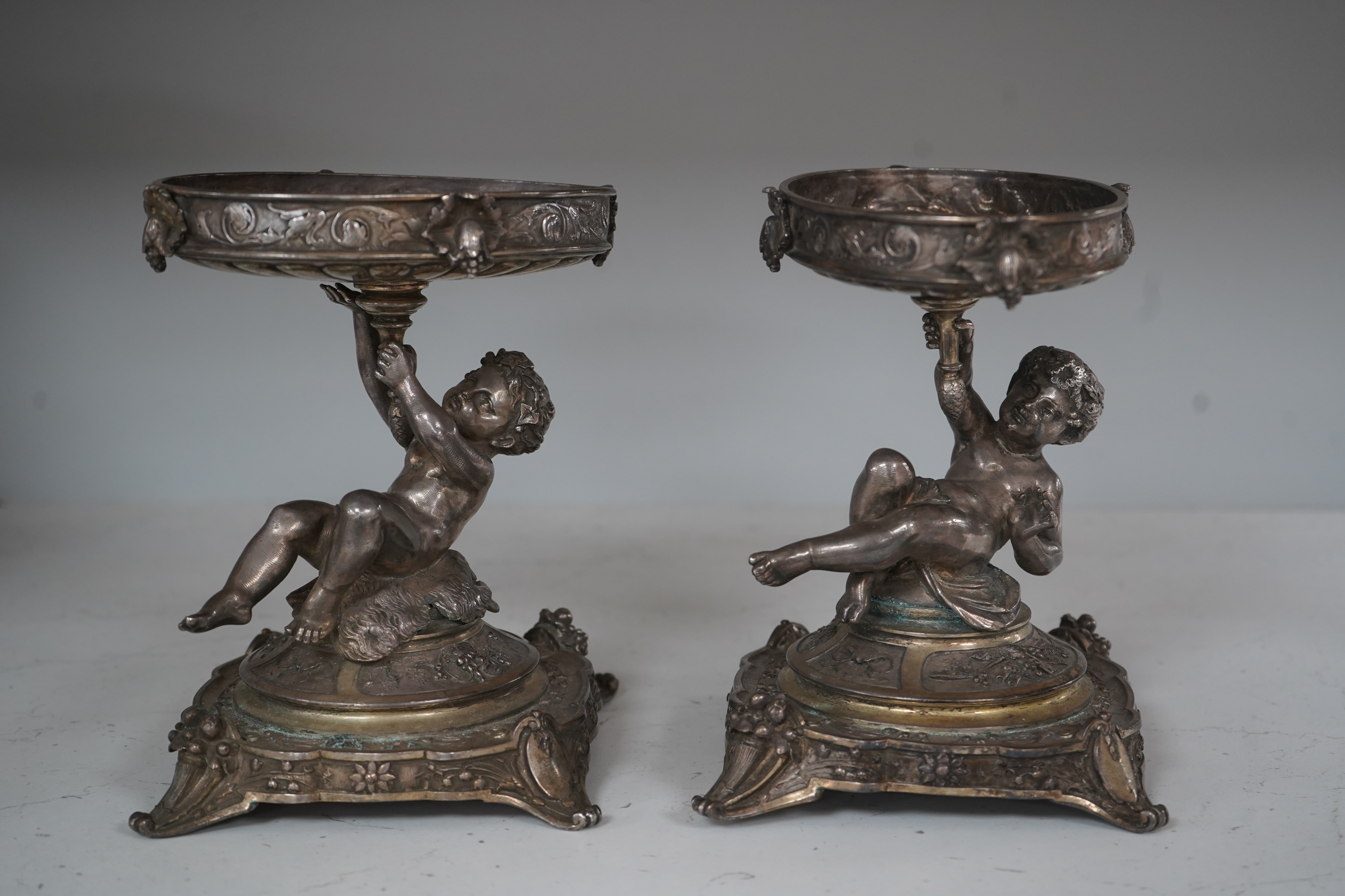 A pair of early 20th century Elkington & Co. silver plated ‘putti’ stands, 17cm. Condition - fair to good